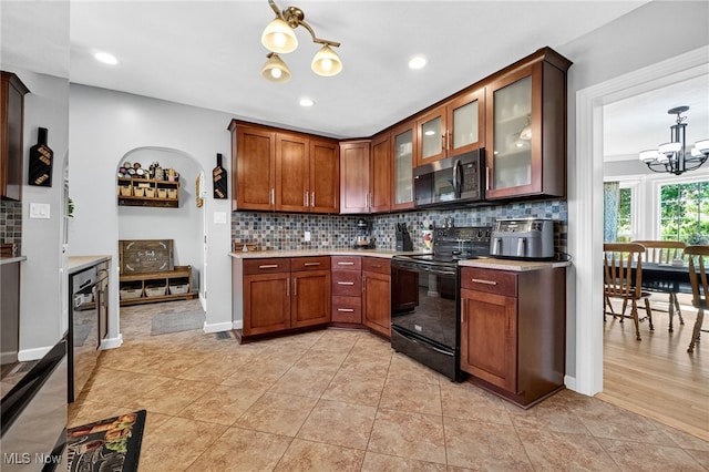 3905 Greenwich Rd, Norton, OH 44203 - kitchen with black / electric stove, a chandelier, light countertops, backsplash, and glass insert cabinets
