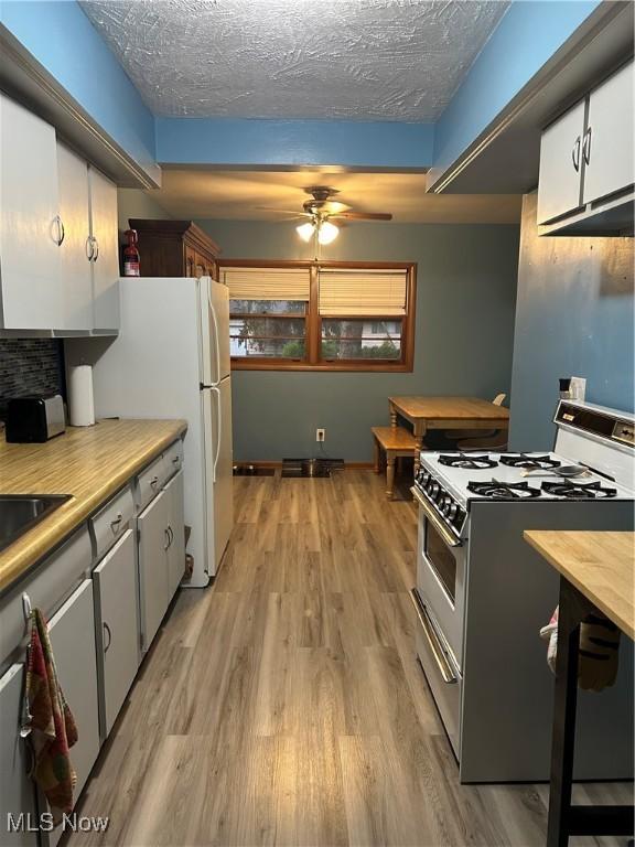 1345 Autumn Dr NW, Warren, OH 44485 - kitchen with white appliances, light wood finished floors, a ceiling fan, light countertops, and a textured ceiling