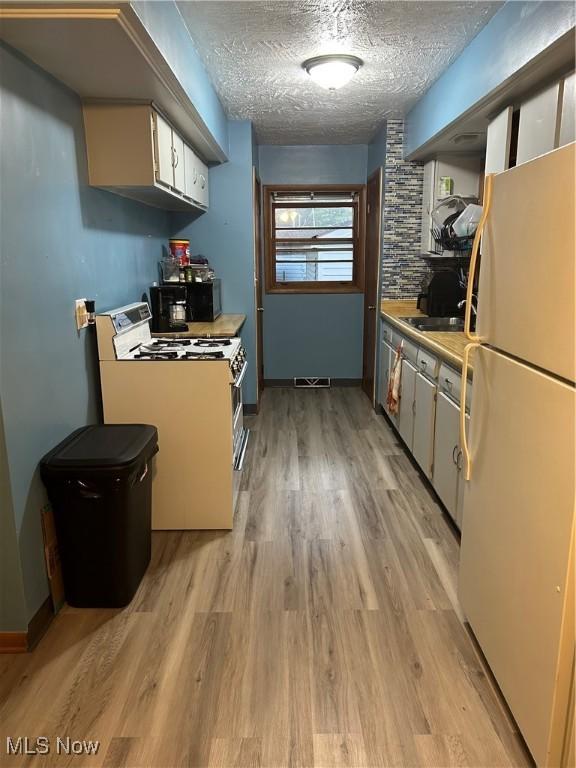 1345 Autumn Dr NW, Warren, OH 44485 - kitchen with white appliances, light wood-style floors, light countertops, white cabinetry, and a textured ceiling