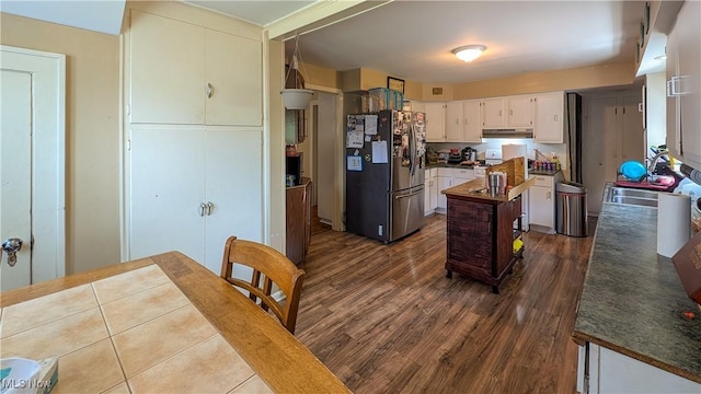 612 W Osborne St, Sandusky, OH 44870 - kitchen with freestanding refrigerator, a kitchen island, under cabinet range hood, dark wood-style floors, and dark countertops