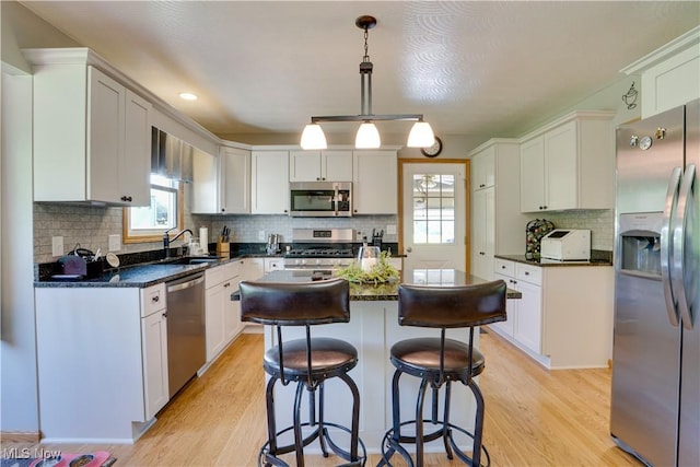 2939 Sandhill Rd, Marietta, OH 45750 - kitchen with stainless steel appliances, light wood-style flooring, a center island, decorative backsplash, and a kitchen breakfast bar