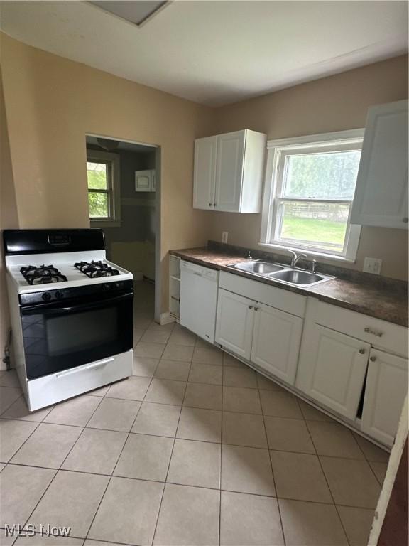 1012 Chandler Ave, Akron, OH 44314 - kitchen with white appliances, healthy amount of natural light, white cabinets, and light tile patterned flooring