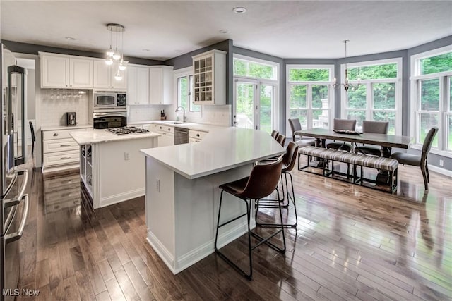18367 Cranberry Ridge Ln, Chagrin Falls, OH 44023 - kitchen with stainless steel appliances, a kitchen breakfast bar, light countertops, dark wood-style flooring, and a center island