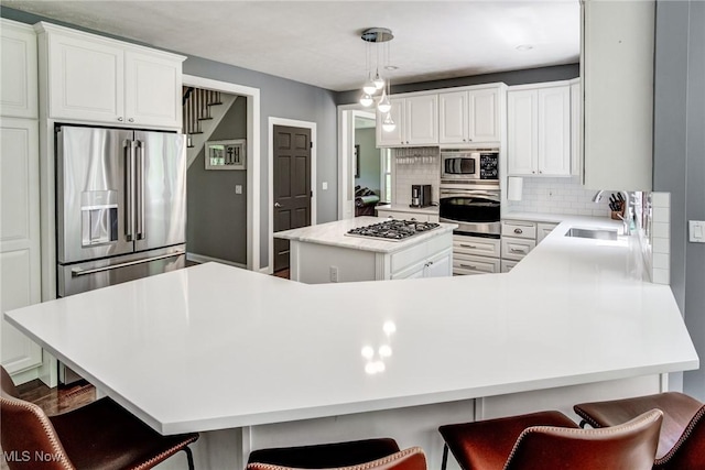 18367 Cranberry Ridge Ln, Chagrin Falls, OH 44023 - kitchen featuring stainless steel appliances, decorative backsplash, white cabinetry, a kitchen island, and light countertops