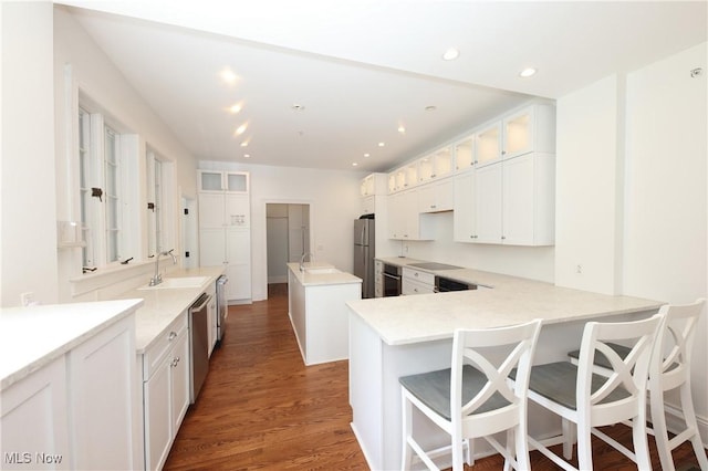 12 Lotus Ave, Chester, WV 26034 - kitchen with appliances with stainless steel finishes, glass insert cabinets, wood finished floors, a kitchen island, and white cabinetry
