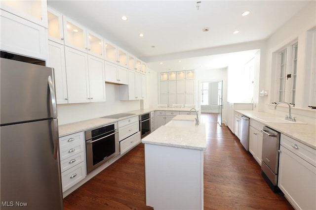 12 Lotus Ave, Chester, WV 26034 - kitchen featuring appliances with stainless steel finishes, a kitchen island with sink, white cabinets, light stone counters, and glass insert cabinets