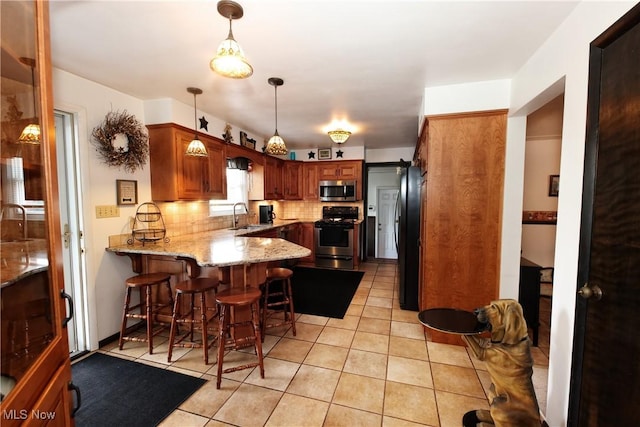 27 Robinson Ln, Weirton, WV 26062 - kitchen featuring stainless steel appliances, a peninsula, light stone counters, backsplash, and light tile patterned floors