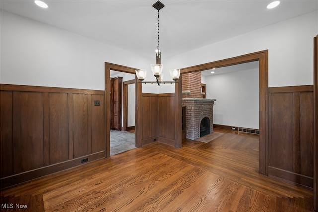 159 Edgerton Rd, Akron, OH 44303 - unfurnished living room featuring a wainscoted wall, a chandelier, wood finished floors, a brick fireplace, and recessed lighting