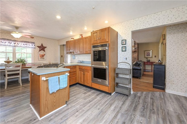 3043 E Wallings Rd, Broadview Heights, OH 44147 - kitchen featuring wallpapered walls, stainless steel appliances, a ceiling fan, a peninsula, and light wood-style flooring