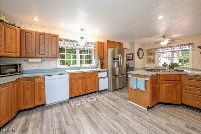 3043 E Wallings Rd, Broadview Heights, OH 44147 - kitchen with appliances with stainless steel finishes, wallpapered walls, brown cabinetry, light wood-type flooring, and plenty of natural light