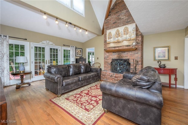 3043 E Wallings Rd, Broadview Heights, OH 44147 - living room featuring french doors, wood finished floors, a brick fireplace, vaulted ceiling, and rail lighting