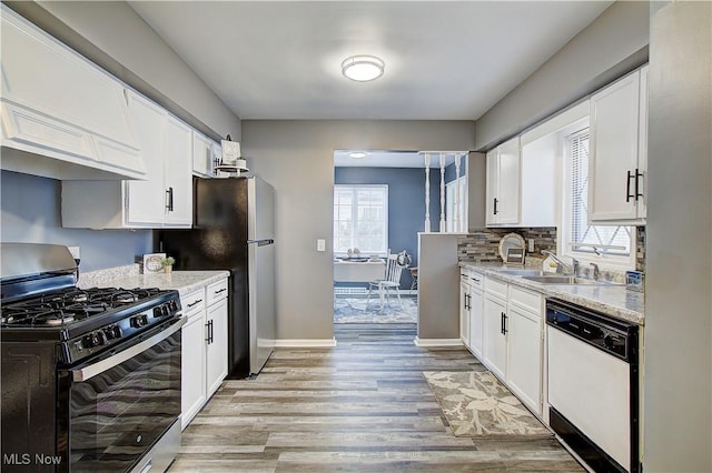 1648 Frederick Ave SW, Canton, OH 44706 - kitchen with white dishwasher, range with gas stovetop, light wood-type flooring, freestanding refrigerator, and white cabinetry