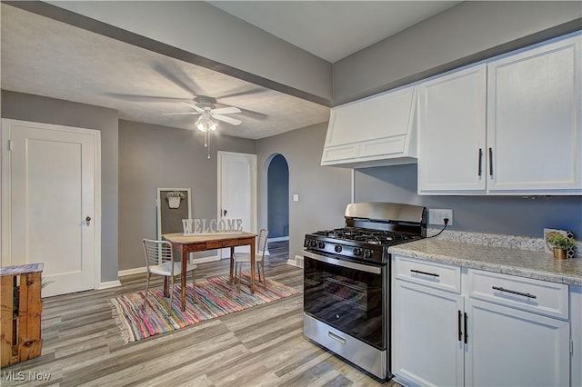 1648 Frederick Ave SW, Canton, OH 44706 - kitchen featuring stainless steel range with gas cooktop, arched walkways, light wood-type flooring, white cabinetry, and custom exhaust hood