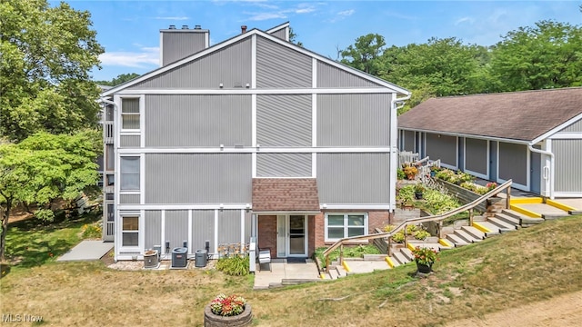 255 Portage Lakes Dr Unit E, Akron, OH 44319 - rear view of house featuring a patio area, a chimney, brick siding, and a yard