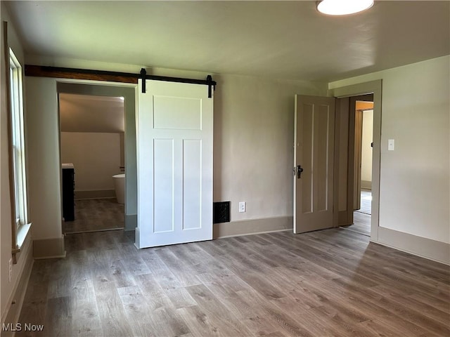 26 E Satin St, Jefferson, OH 44047 - unfurnished bedroom with wood finished floors and a barn door