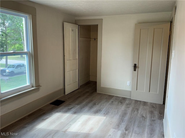 26 E Satin St, Jefferson, OH 44047 - unfurnished bedroom with wood finished floors, multiple windows, a textured ceiling, and a closet