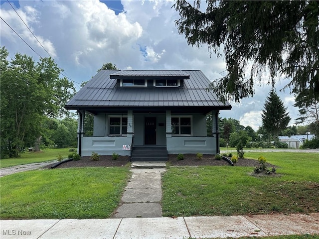 26 E Satin St, Jefferson, OH 44047 - bungalow-style home with a standing seam roof, a porch, a front lawn, stucco siding, and a metal roof