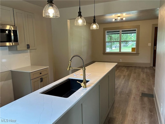 26 E Satin St, Jefferson, OH 44047 - kitchen with stainless steel microwave, wood finished floors, hanging light fixtures, and light stone countertops