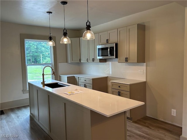 26 E Satin St, Jefferson, OH 44047 - kitchen with stainless steel microwave, dark wood-style flooring, a kitchen island with sink, pendant lighting, and light countertops