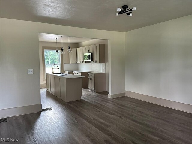 26 E Satin St, Jefferson, OH 44047 - kitchen with stainless steel microwave, dark wood-style flooring, a center island with sink, pendant lighting, and gray cabinets