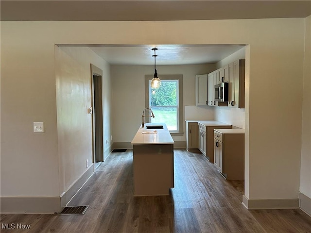 26 E Satin St, Jefferson, OH 44047 - kitchen featuring dark wood-type flooring, a center island with sink, stainless steel microwave, pendant lighting, and light countertops
