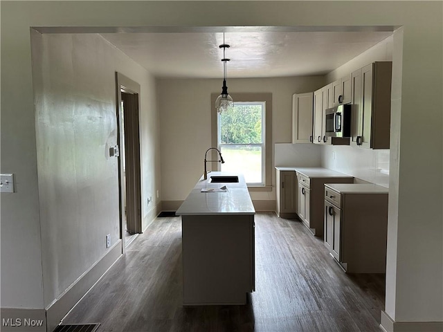 26 E Satin St, Jefferson, OH 44047 - kitchen with stainless steel microwave, wood finished floors, an island with sink, and light countertops
