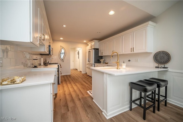 117 Nicklaus Dr NE, Warren, OH 44484 - kitchen with freestanding refrigerator, a peninsula, white cabinets, decorative backsplash, and light wood-type flooring