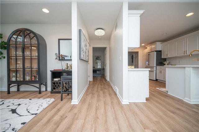 117 Nicklaus Dr NE, Warren, OH 44484 - kitchen featuring stainless steel fridge, light wood-style flooring, light countertops, arched walkways, and recessed lighting