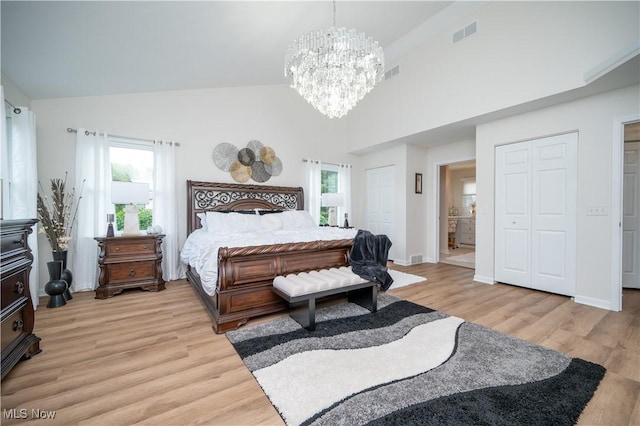 117 Nicklaus Dr NE, Warren, OH 44484 - bedroom featuring a chandelier, light wood-style floors, high vaulted ceiling, two closets, and multiple windows