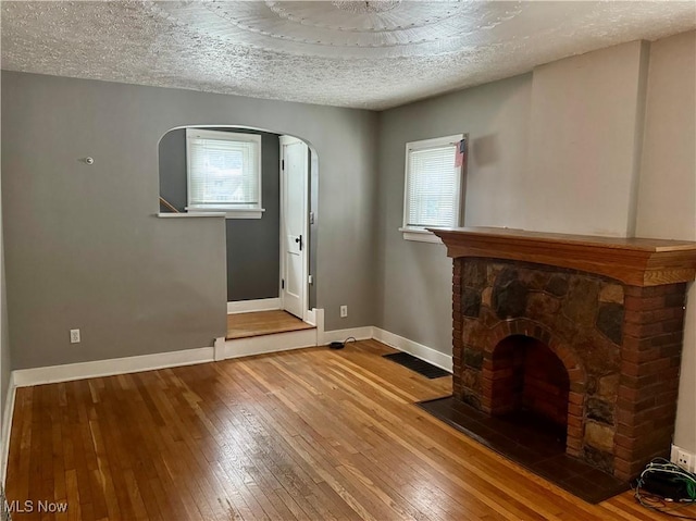 667 Eastland Ave, Akron, OH 44305 - foyer with arched walkways, hardwood / wood-style flooring, a textured ceiling, and a stone fireplace