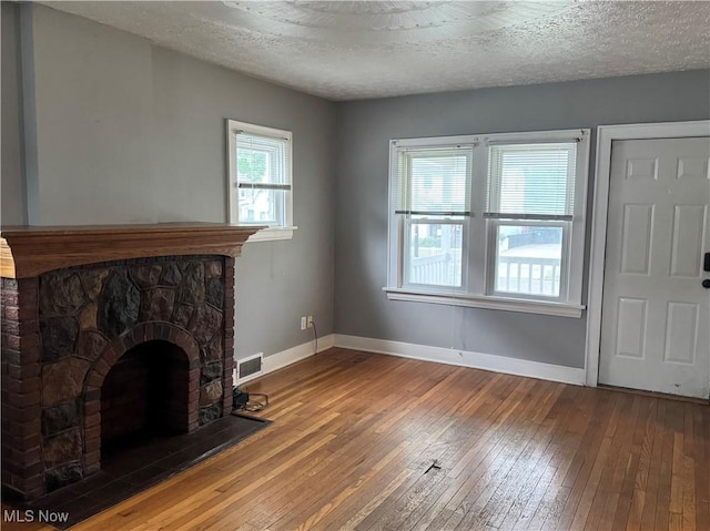 667 Eastland Ave, Akron, OH 44305 - unfurnished living room with hardwood / wood-style flooring, a stone fireplace, and a textured ceiling