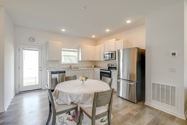 677 Crossings Ln, Akron, OH 44320 - kitchen featuring appliances with stainless steel finishes, light wood-style flooring, light countertops, white cabinetry, and recessed lighting