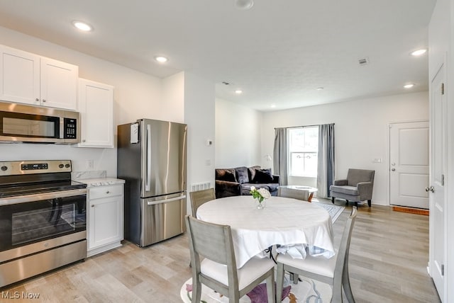 677 Crossings Ln, Akron, OH 44320 - kitchen with stainless steel appliances, light wood-style floors, open floor plan, white cabinets, and recessed lighting