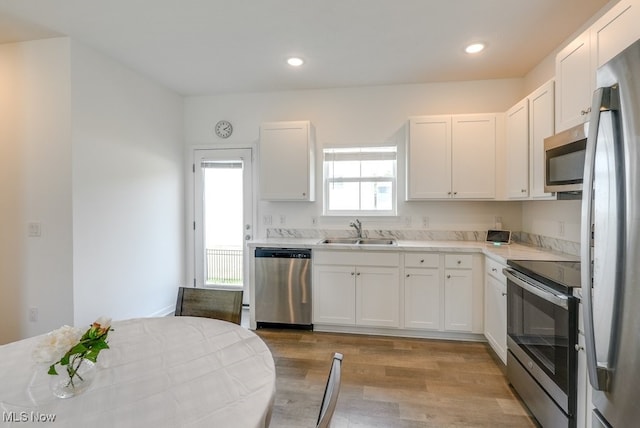 677 Crossings Ln, Akron, OH 44320 - kitchen featuring appliances with stainless steel finishes, light wood-style floors, light countertops, white cabinets, and recessed lighting