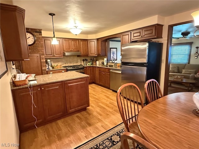 120 Kennedy Ave, Follansbee, WV 26037 - kitchen featuring under cabinet range hood, appliances with stainless steel finishes, light wood-type flooring, light stone countertops, and a peninsula