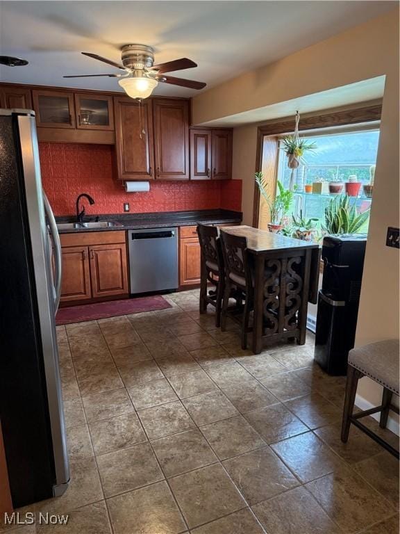 9237 Shephard Rd, Macedonia, OH 44056 - kitchen featuring stainless steel appliances, dark countertops, backsplash, a ceiling fan, and brown cabinetry