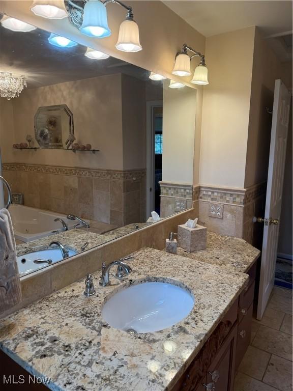 9237 Shephard Rd, Macedonia, OH 44056 - full bathroom with tile walls, vanity, a tub with jets, and wainscoting