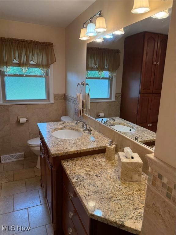 9237 Shephard Rd, Macedonia, OH 44056 - bathroom with vanity, a wainscoted wall, tile walls, and stone tile flooring