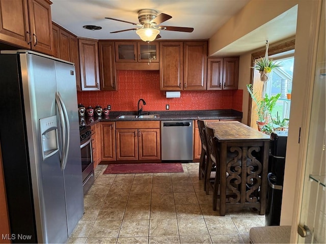 9237 Shephard Rd, Macedonia, OH 44056 - kitchen featuring stainless steel appliances, dark countertops, ceiling fan, backsplash, and brown cabinets