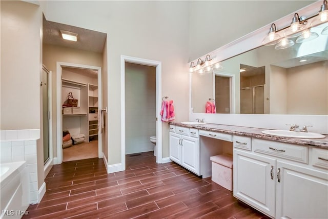 9798 Firestone Ln, Macedonia, OH 44056 - bathroom with double vanity, a stall shower, wood finished floors, a garden tub, and a spacious closet