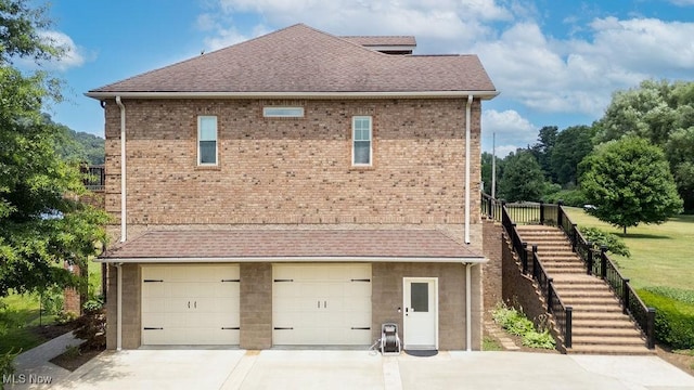 390 Powell Riverfront Rd, Saint Marys, WV 26170 - view of side of property featuring stairs, a garage, driveway, roof with shingles, and brick siding