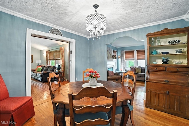 2107 13th St, Cuyahoga Falls, OH 44223 - dining area featuring arched walkways, light wood-style flooring, a chandelier, ornamental molding, and a textured ceiling