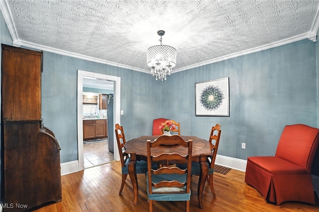 2107 13th St, Cuyahoga Falls, OH 44223 - dining area featuring hardwood / wood-style flooring, a chandelier, a textured ceiling, and crown molding