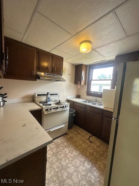 195 Water St, Wadsworth, OH 44281 - kitchen featuring freestanding refrigerator, white range with gas stovetop, under cabinet range hood, dark brown cabinetry, and light countertops