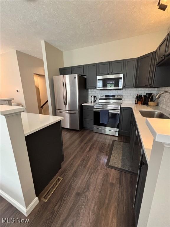 1314 Wellingshire Cir, Cuyahoga Falls, OH 44221 - kitchen with appliances with stainless steel finishes, a textured ceiling, dark wood-style floors, light countertops, and decorative backsplash