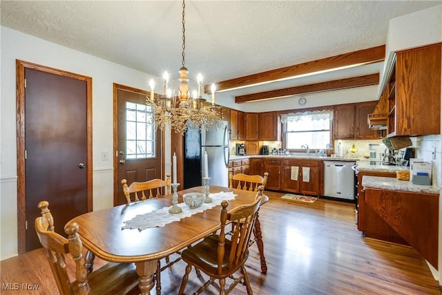10154 Carlswood Ave NE, Hartville, OH 44632 - dining space with a chandelier, light wood-type flooring, a textured ceiling, and beam ceiling