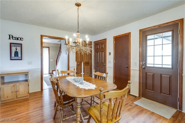 10154 Carlswood Ave NE, Hartville, OH 44632 - dining area featuring a chandelier, stairway, and light wood-style flooring