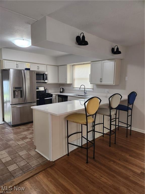 16805 Scottsdale Blvd, Shaker Heights, OH 44120 - kitchen featuring stainless steel appliances, a peninsula, a breakfast bar, light countertops, and white cabinetry