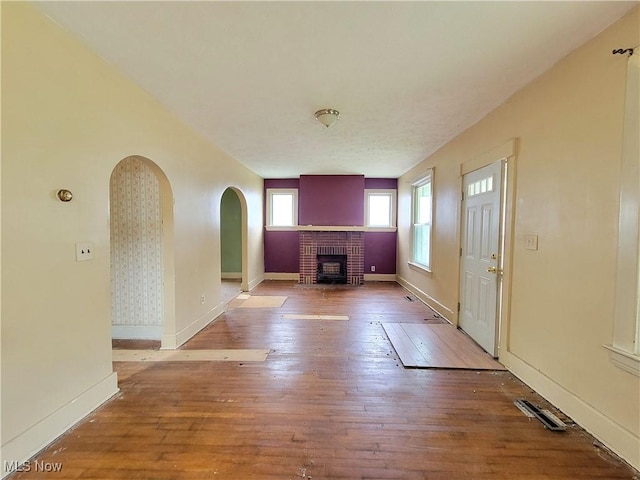 1707 23rd St, Parkersburg, WV 26101 - unfurnished living room featuring a fireplace, arched walkways, and wood-type flooring