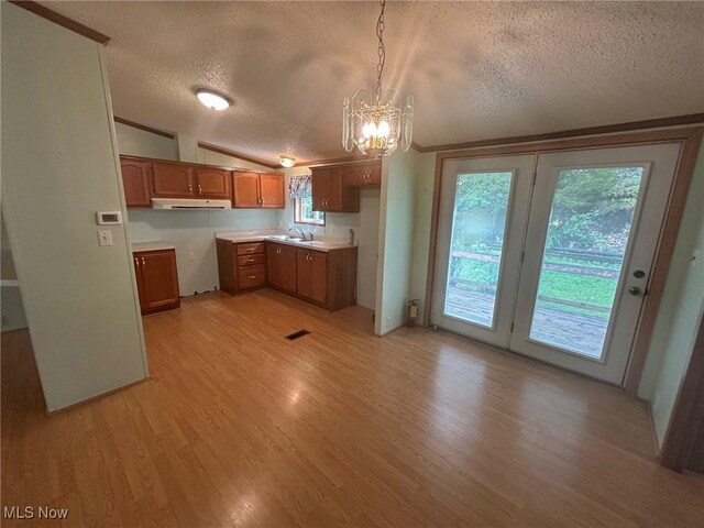 355 Muskingum River Rd, Marietta, OH 45750 - kitchen featuring a textured ceiling, under cabinet range hood, brown cabinetry, a chandelier, and light wood finished floors